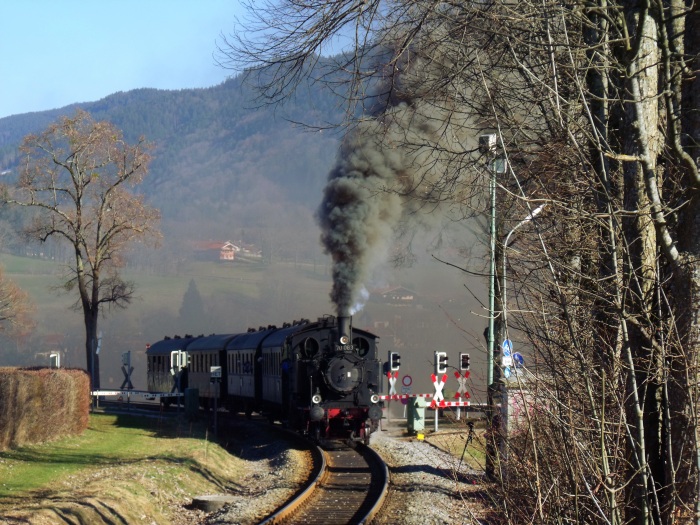 70 083 mit dem zweiten, dem nachmittäglichen Zug des Bayrischen Localbahnvereins von Tegernsee nach Holzkirchen, fotografiert direkt am Bundestraßen-Bahnübergang hinter Gmund, mit ein wenig Alpen-Kulisse im Hintergrund, NOCH lauter als am Vormittag bergfahrend, um 15:27h am 12.03.2017