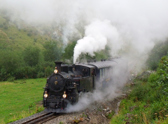 FO 4 mit Zug Realp-Oberwald, im Furkareusstal unterhalb vom Haltepunkt Tiefenbach im heftigen und strömenden Regen, den man hier auch deutlich sehen kann, um 10:34h am 15.08.2015