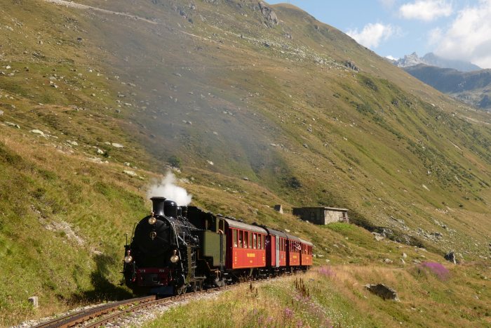 Lok 704 DFB mit dem ersten Zug des Tages (Nr.133) Realp-Oberwald, fotografiert etwa bei Streckenkilometer 52,7 unterhalb vom Bahnhof Furka, um 10:51h am 11.08.2022