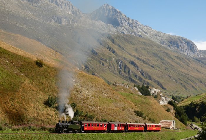 704  mit Zug Nr.133 Realp->Oberwald auf dem Bahndamm am Nordhang vor den Wilerbrücken, um 10:27h am 13.08.2022