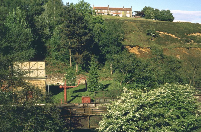 In Frühlingsfarben und im Abendlicht sieht der Blick über den Eller Beck auf das südliche Ende der Station Goathland mit Wasserturm und Wasserkran an der Flussbrücke richtig hübsch aus, um 18:00h am 30.05.2002
